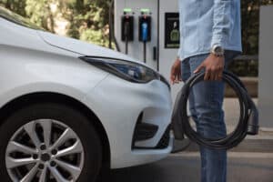 vista lateral hombre sujetando cable coche Curso de cargadores eléctricos Jaén